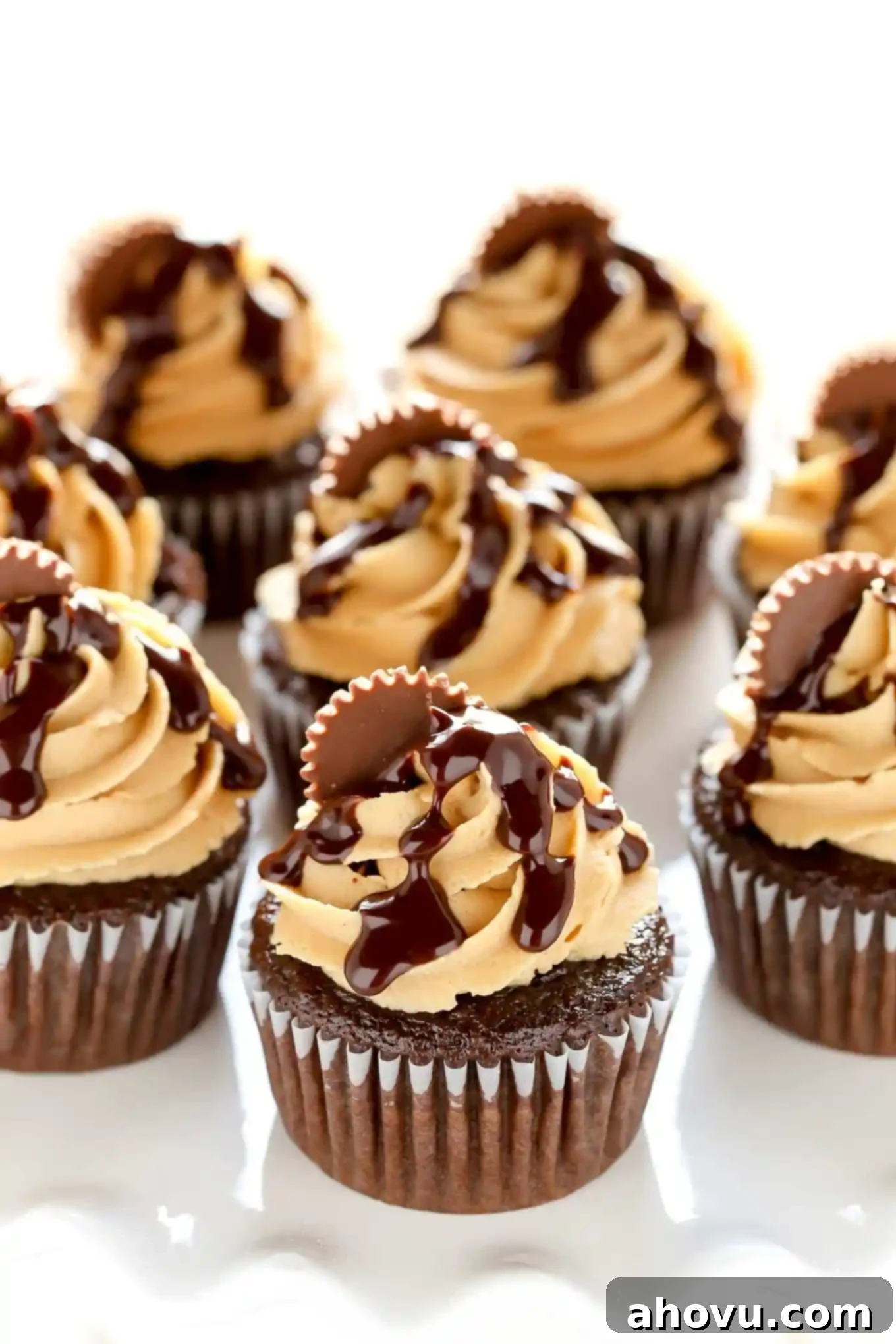Chocolate cupcakes with fluffy peanut butter frosting beautifully piped on top, arranged on a pristine white cake stand, ready to be adorned with ganache and peanut butter cups.