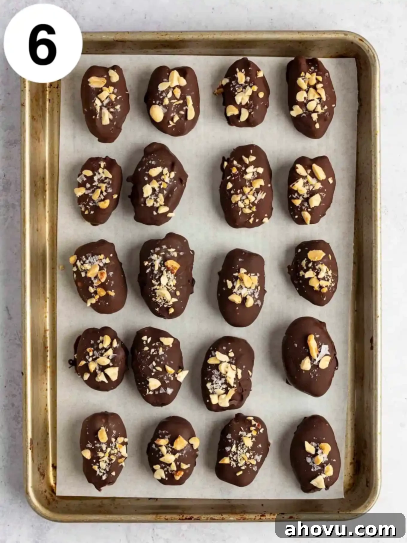 An overhead view of chocolate covered dates lined up on a baking sheet. 