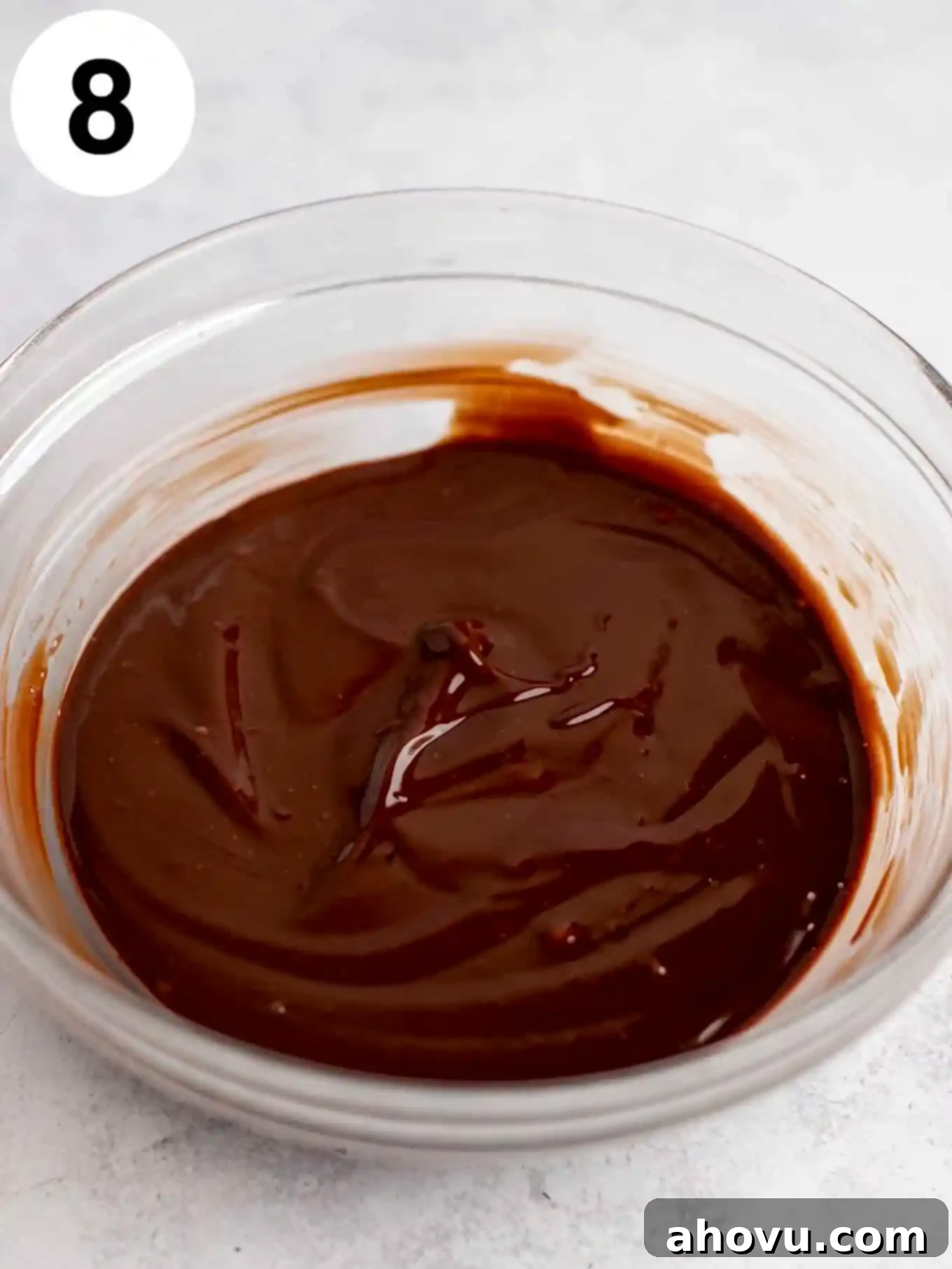 Melted chocolate ganache in a glass mixing bowl. 