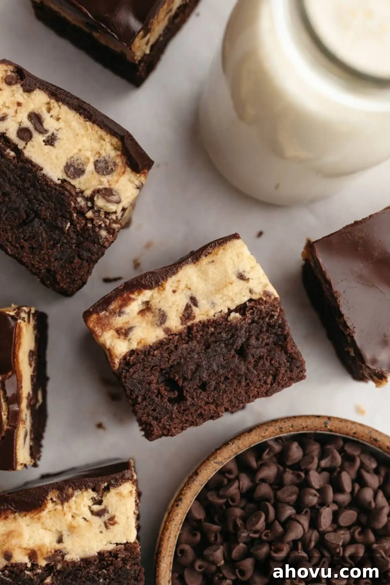 An overhead view of several cookie dough brownies, some turned on their sides, artfully arranged to highlight their rich, multi-layered composition.