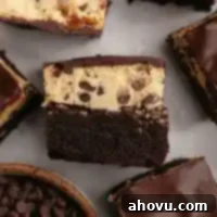 A perfectly portioned cookie dough brownie laying on its side, revealing the distinct layers of chocolate brownie, edible cookie dough, and glossy chocolate topping.