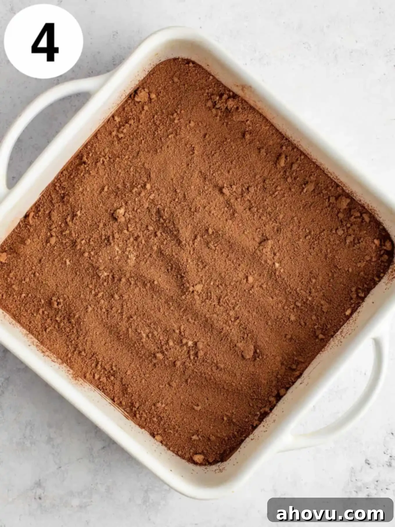 Decadent Chocolate Pudding Cake 7 An overhead view of chocolate cake batter topped with cocoa powder and brown sugar in a baking dish.