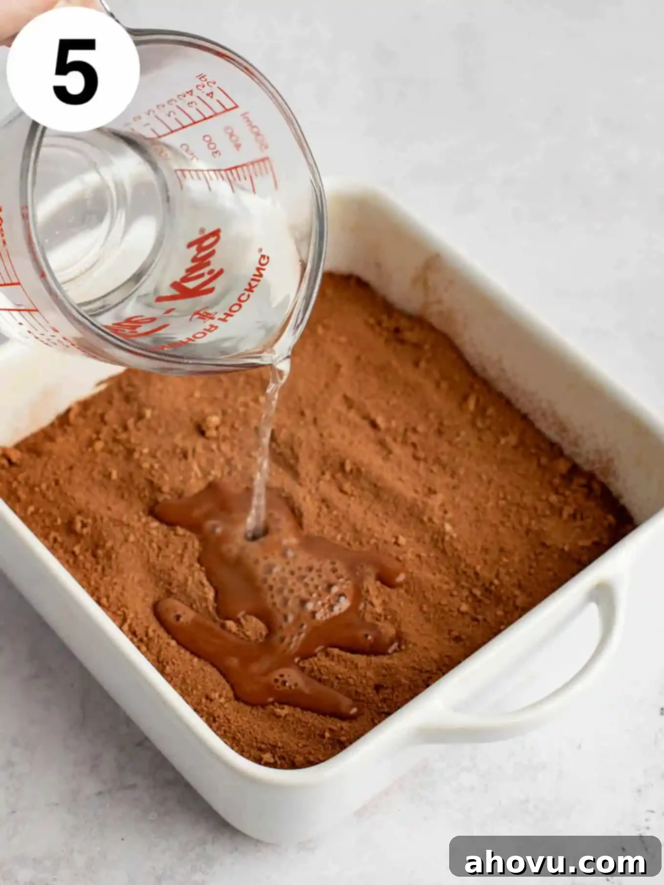 Decadent Chocolate Pudding Cake 8 A process shot showing water being poured over chocolate cake batter in a baking dish.