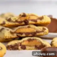 Reese's Peanut Butter Explosion Cookies 12 A stack of chocolate chip cookies stuffed with Reeses that have been cut in half.