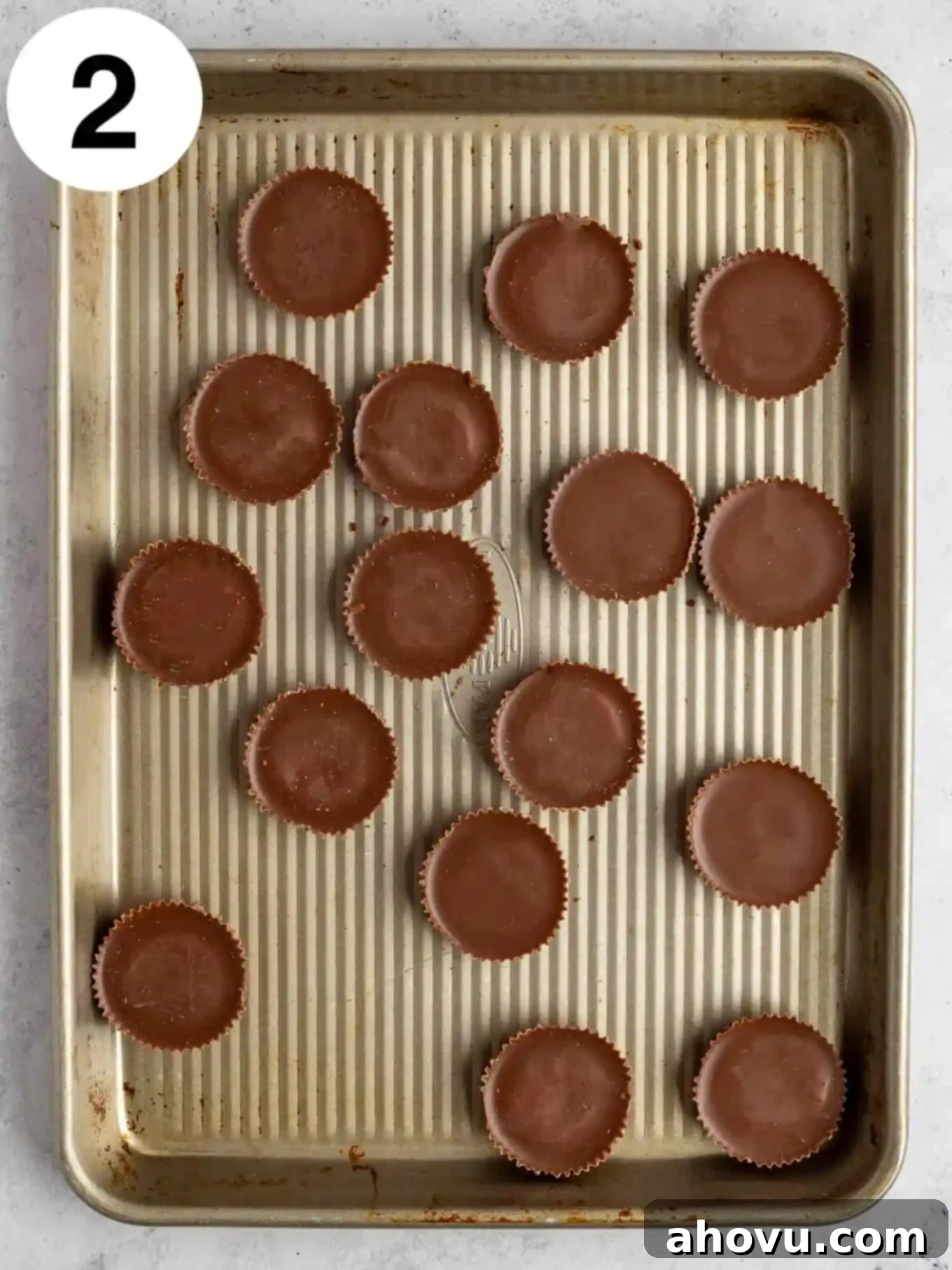 Reese's Peanut Butter Explosion Cookies 5 An overhead view of unwrapped Reese's peanut butter cups on a baking sheet.
