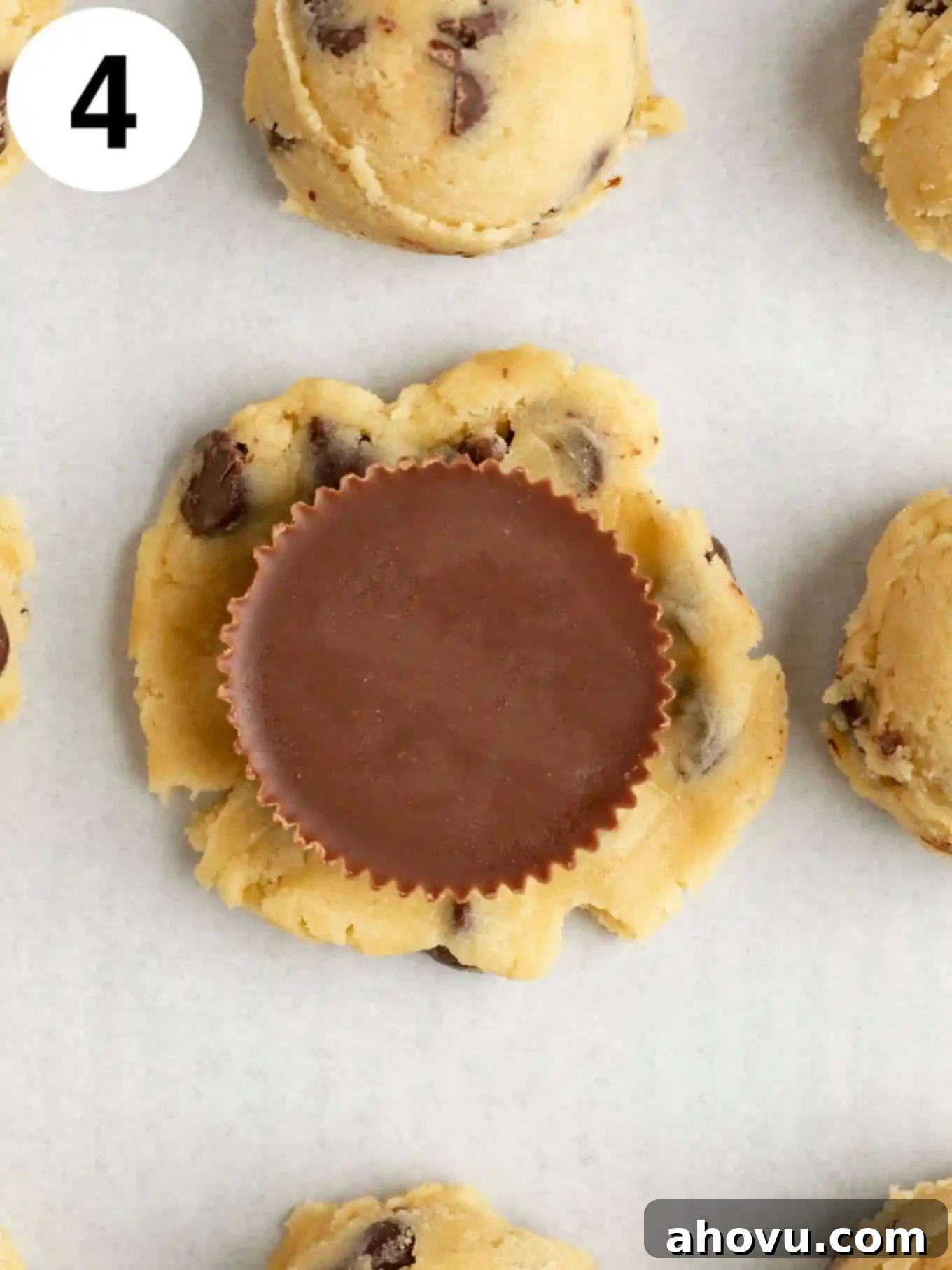 Reese's Peanut Butter Explosion Cookies 7 An overhead view of a circle of chocolate chip cookie dough with a Reese's peanut butter cup in the middle.