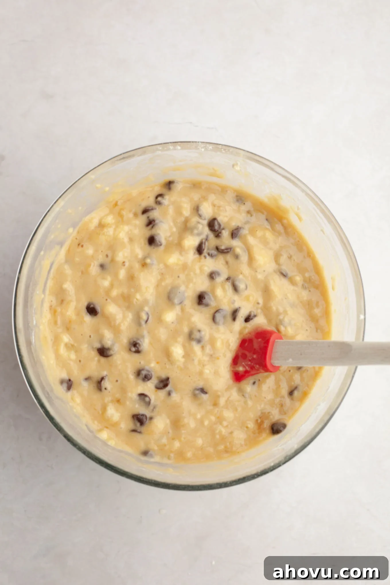 Chocolate chip banana bread batter in a glass mixing bowl, showcasing its consistency.