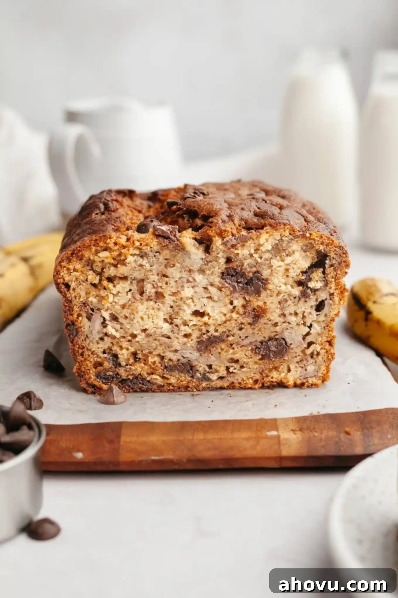 A loaf of sliced banana bread with chocolate chips on a wooden serving board, ready to be enjoyed.