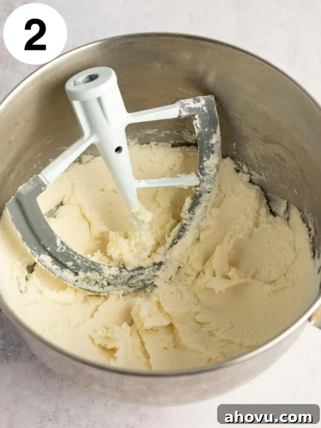 An overhead view of powdered sugar fully mixed into the cream cheese and butter mixture, creating a smooth base.