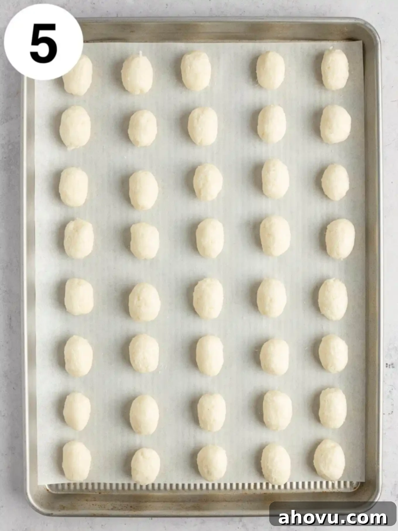 An overhead view of Irish potato candies on a baking sheet, already shaped like small potatoes and waiting for their cinnamon coating.