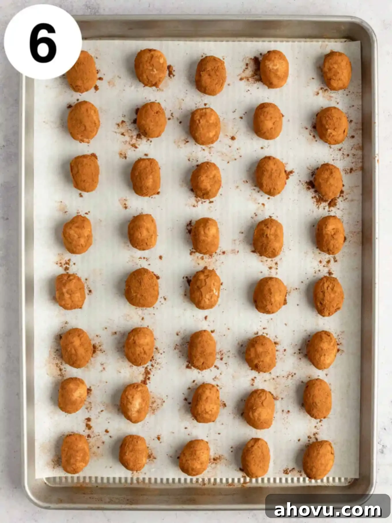 An overhead view of freshly coated cinnamon Irish potato candies neatly arranged on a baking sheet.