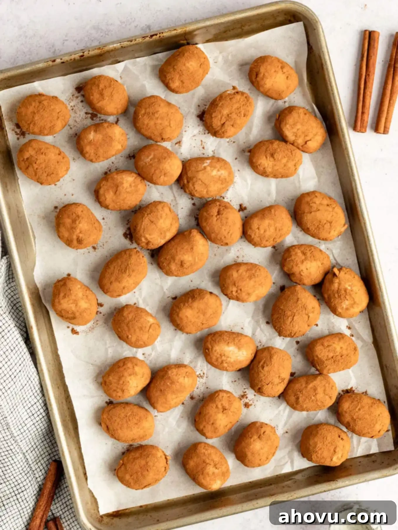 A close-up, overhead view of perfectly coated cinnamon Irish potato candies on a baking sheet, ready to be enjoyed.