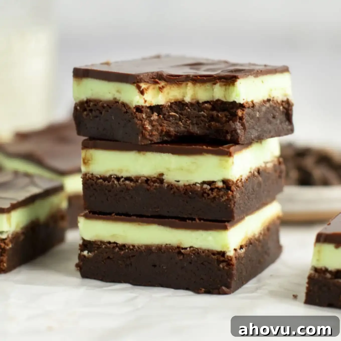 Decadent Mint Chocolate Brownies 12 A delectable stack of mint brownies, with the top brownie showcasing a missing bite, revealing its perfect layers.