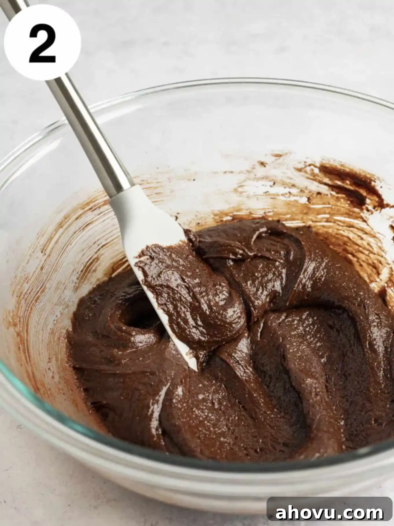 Decadent Mint Chocolate Brownies 5 Thick, glossy chocolate brownie batter perfectly mixed in a clear glass mixing bowl, with a rubber spatula resting inside, showing its rich, dark consistency.