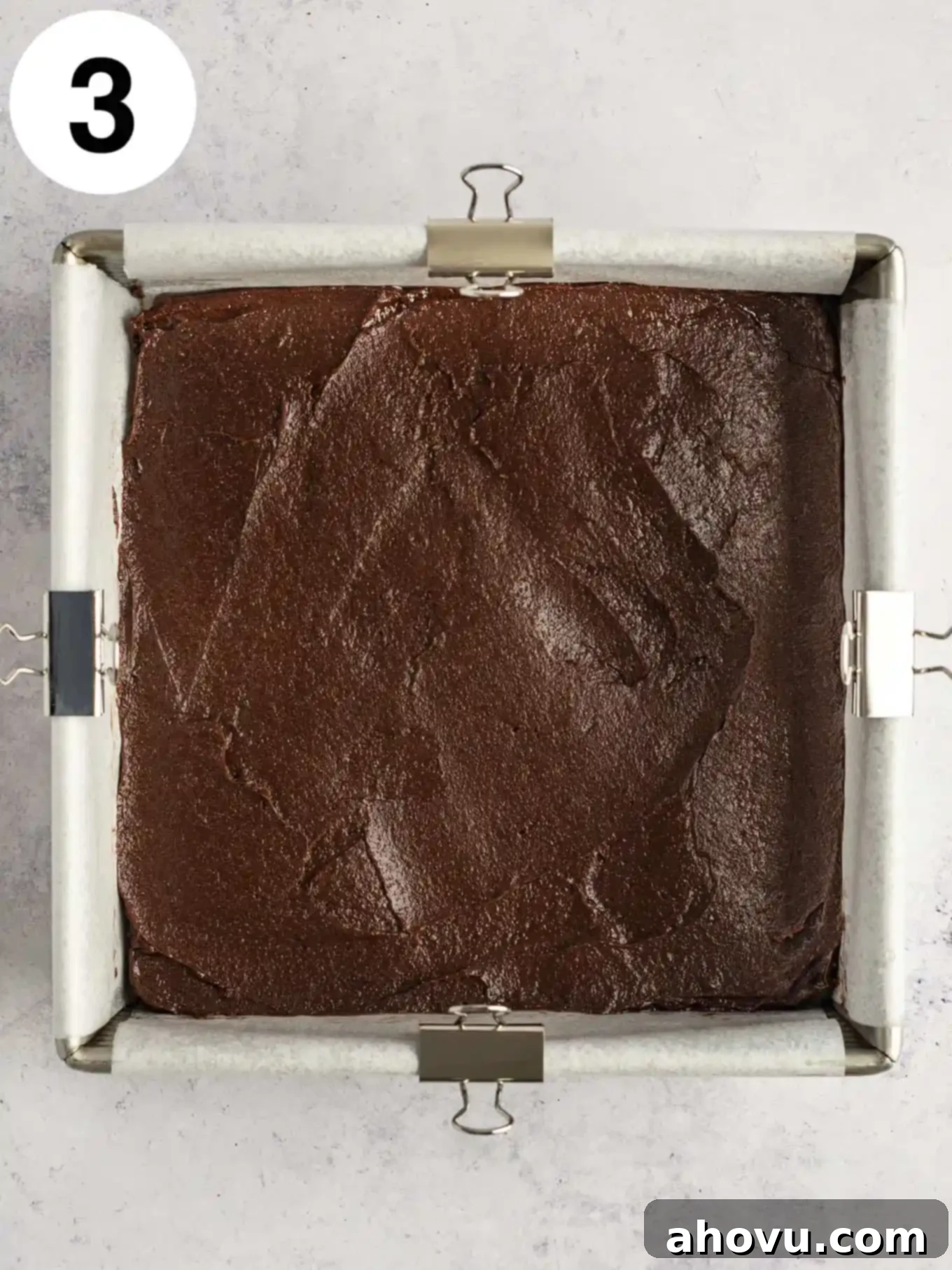 Decadent Mint Chocolate Brownies 6 An overhead shot of glossy, dark raw brownie batter spread evenly within a parchment-lined baking pan, ready for the oven.