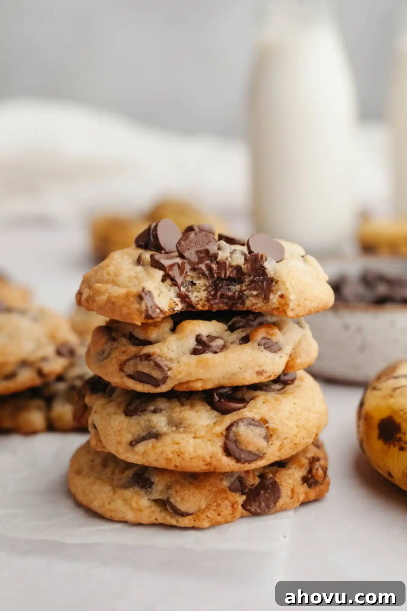 Irresistible Banana Chocolate Chip Cookies 2 A stack of four banana chocolate chip cookies, with the top cookie missing a bite. The cookies are golden brown with melted chocolate chips.