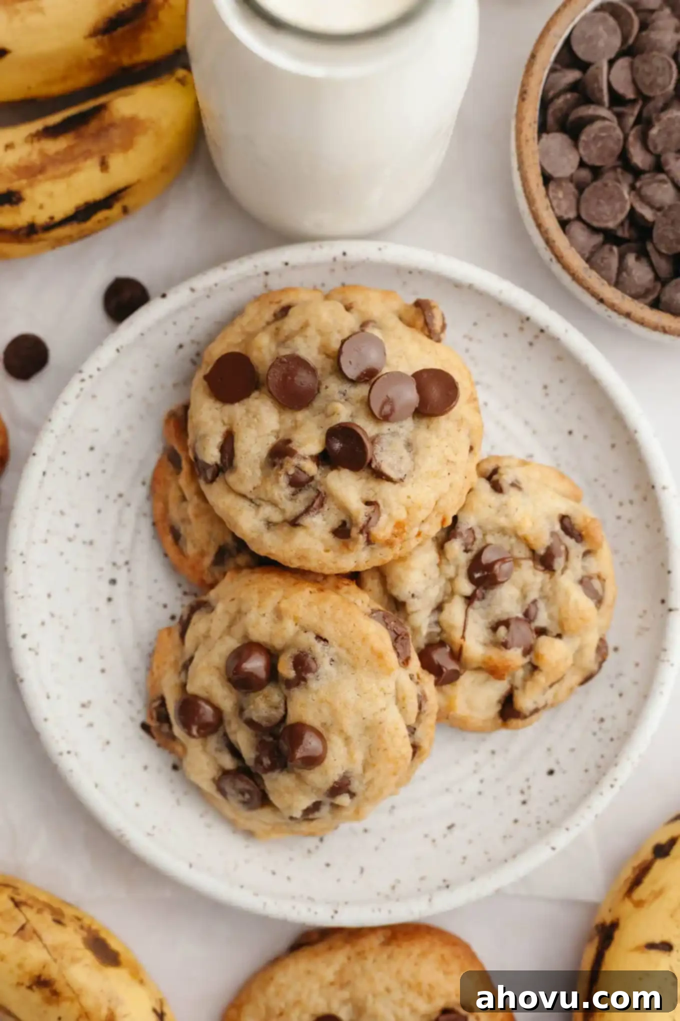 Irresistible Banana Chocolate Chip Cookies 8 An overhead view of banana and chocolate chip cookies piled on a white plate, ready for serving.