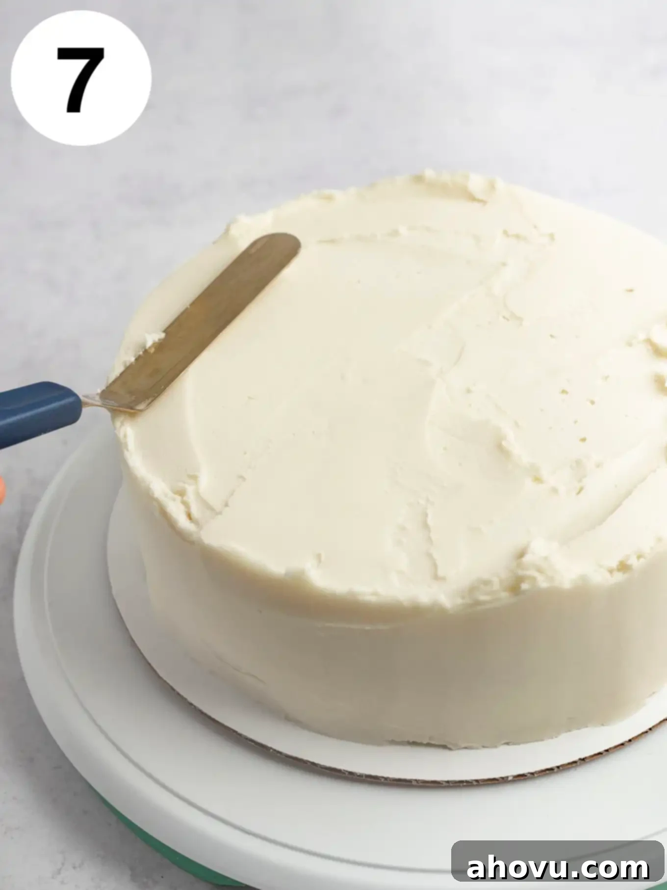 A process shot showing the rough edges of a frosted cake being smoothed out. 