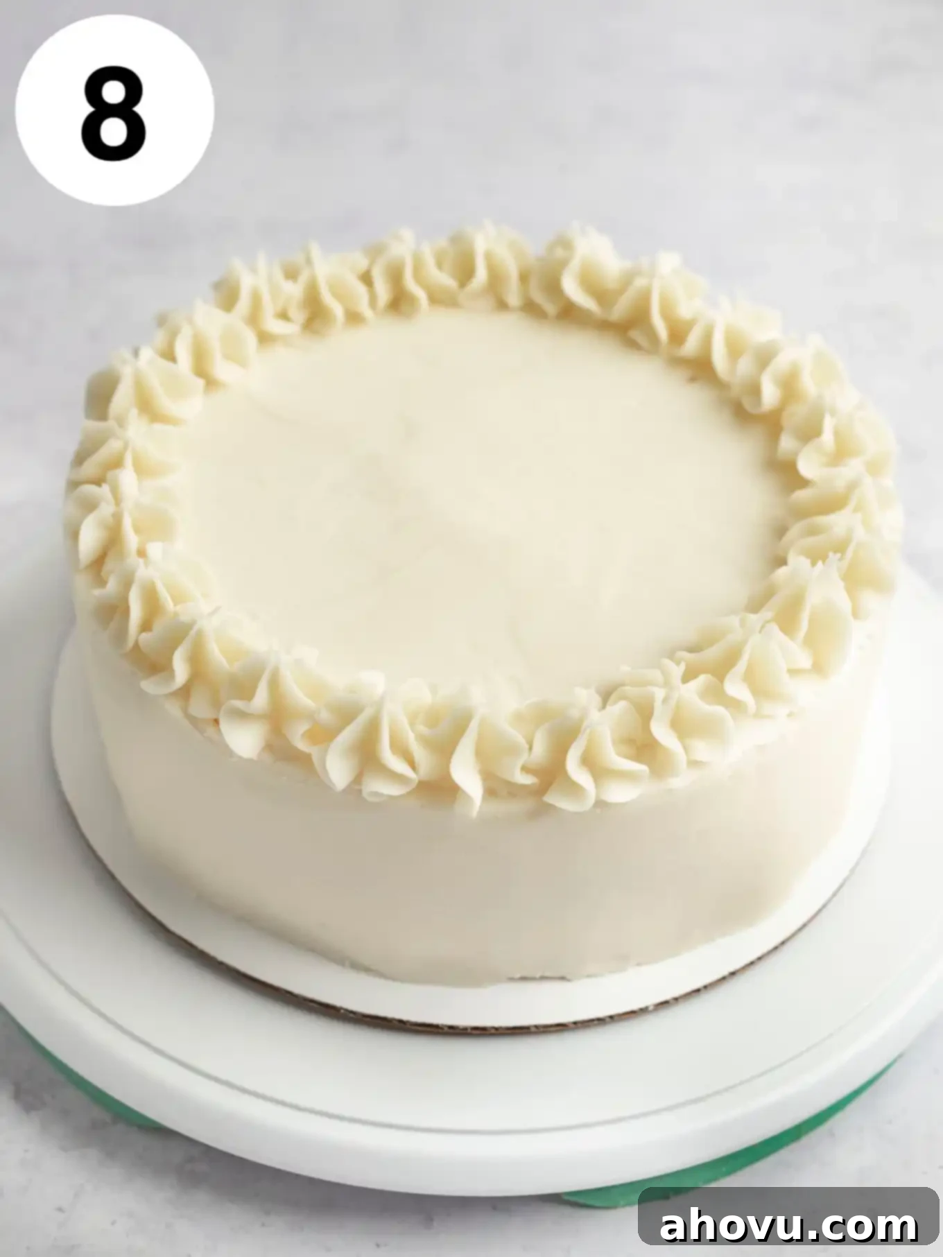 A process shot showing a frosted and decorated white cake on a turntable. 