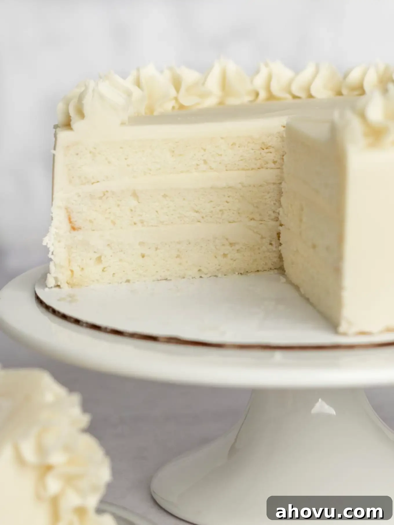 A three layer white cake on a cake stand, sliced to show the inside. 