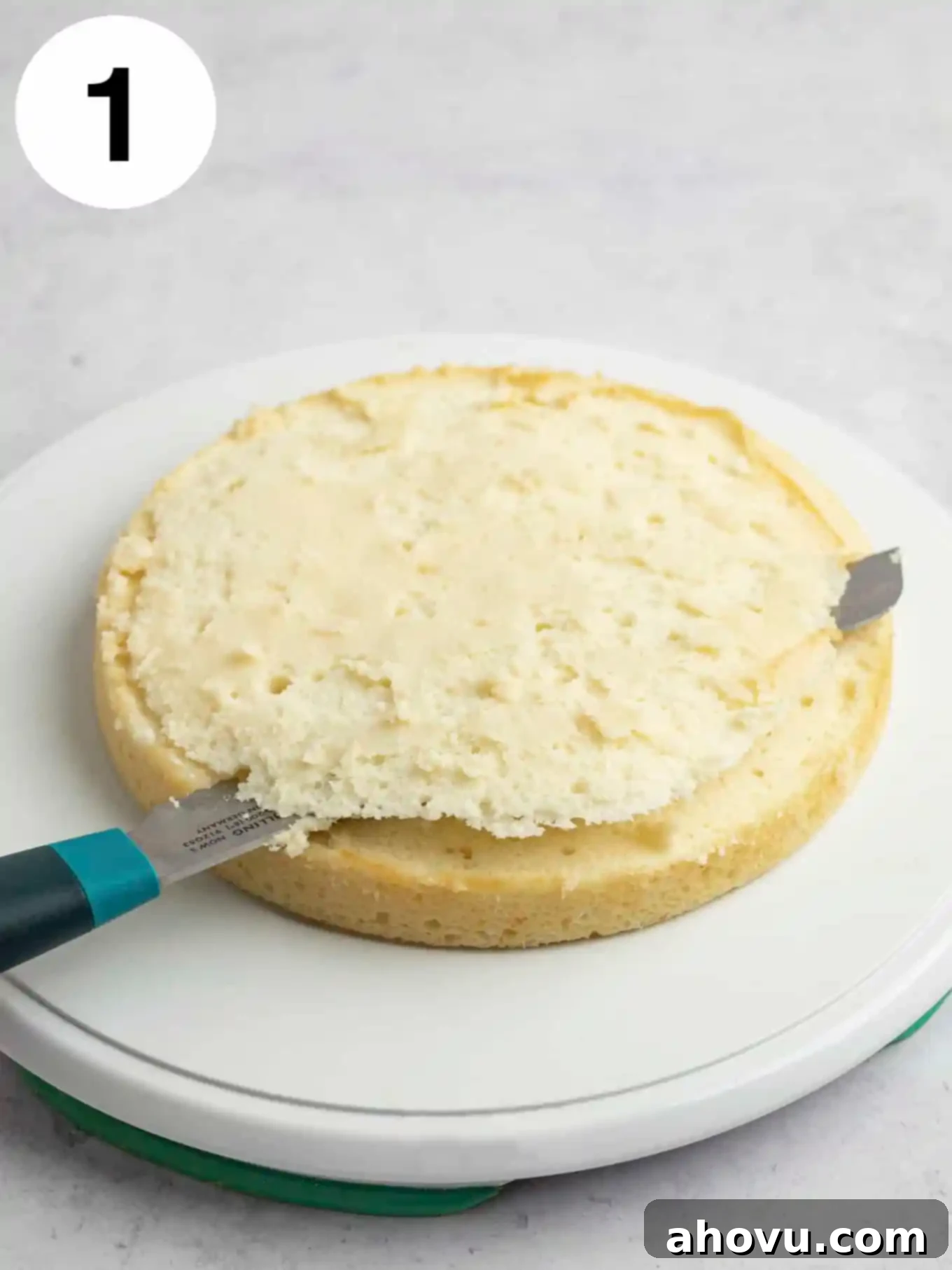 A process shot showing a cake layer being leveled with a serrated knife. 