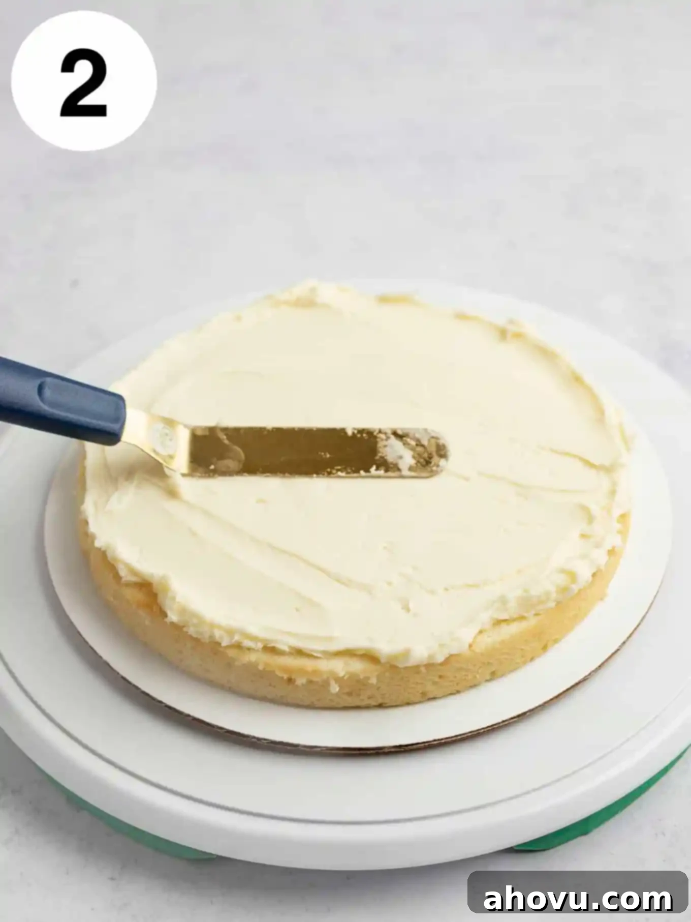 A process shot showing frosting being spread over a bottom cake layer. 