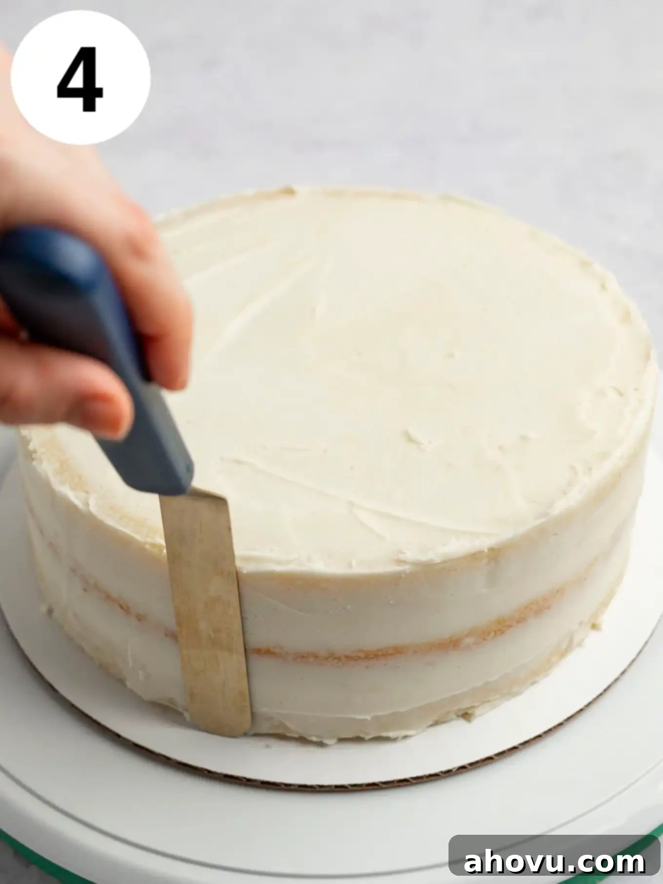A process shot showing a crumb coat being applied with an offset spatula. 