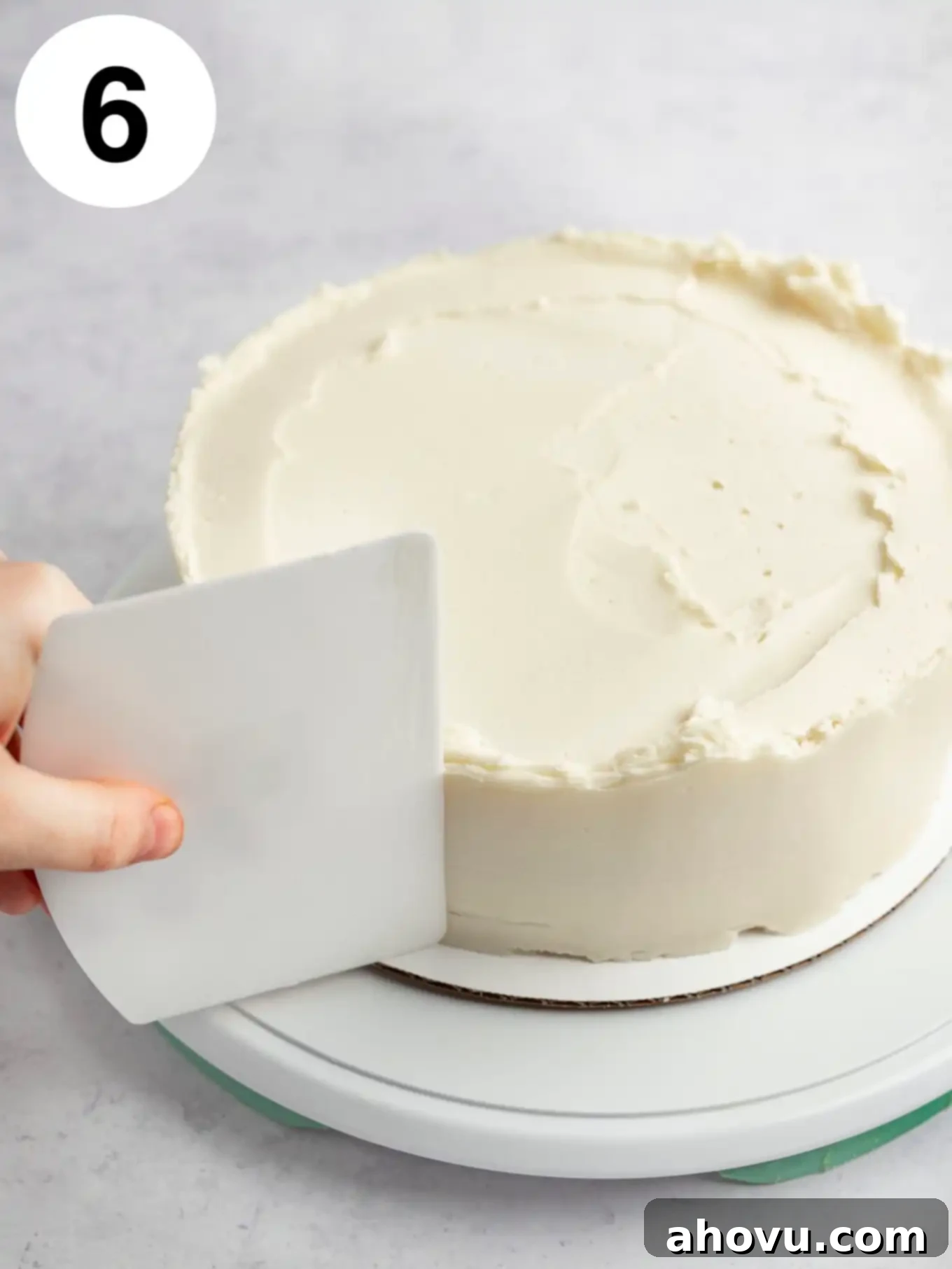 A process shot showing excess frosting being wiped off with a bench scraper. 