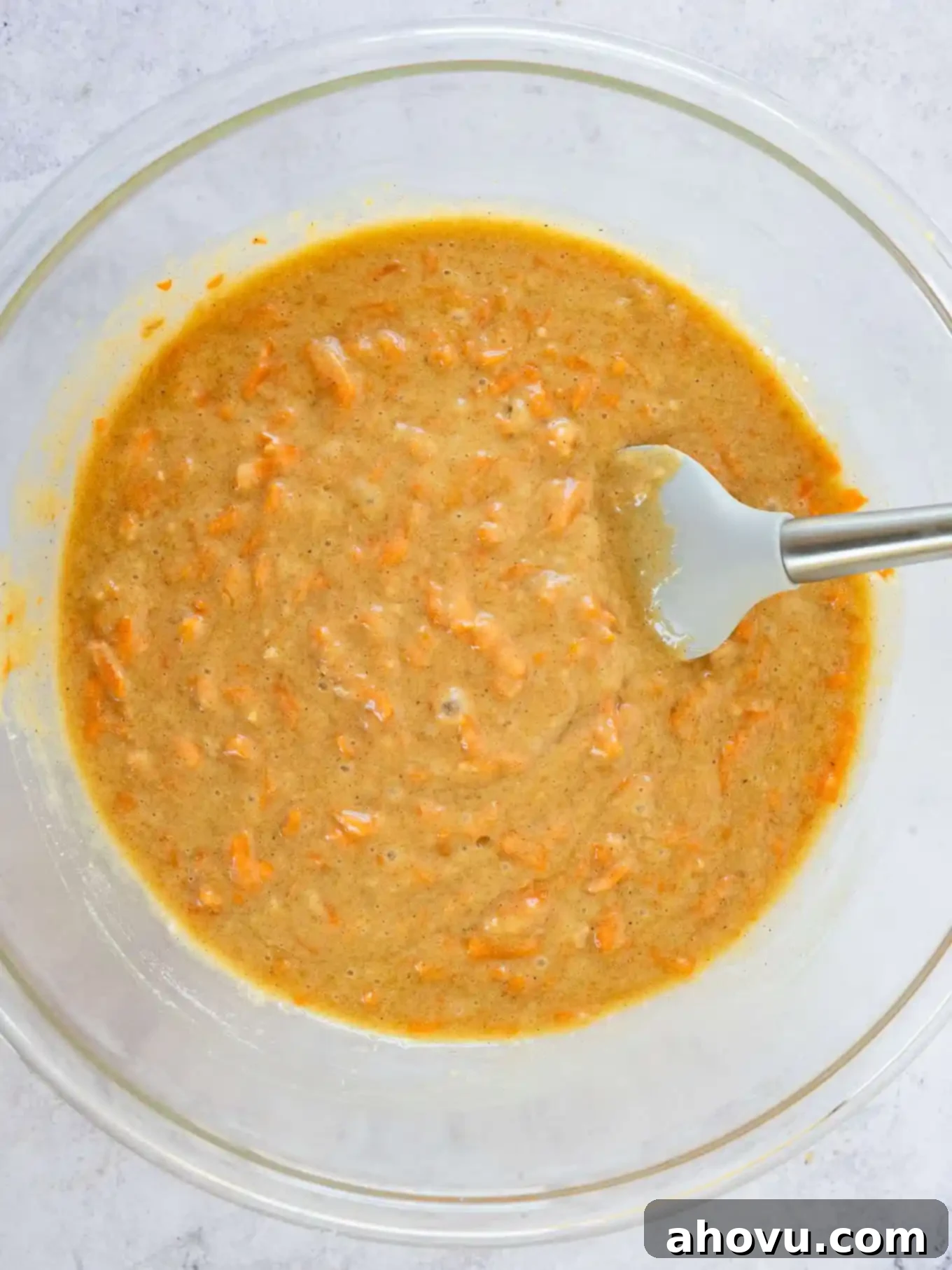 An overhead view of the cake batter in a mixing bowl with a spatula. 