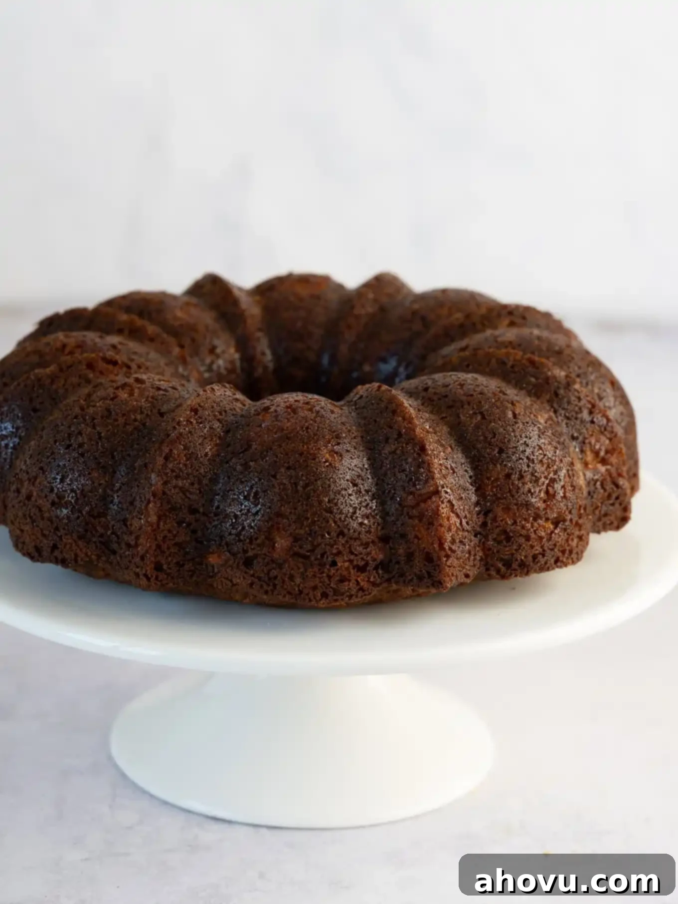 A carrot bundt cake on a cake stand, unfrosted. 