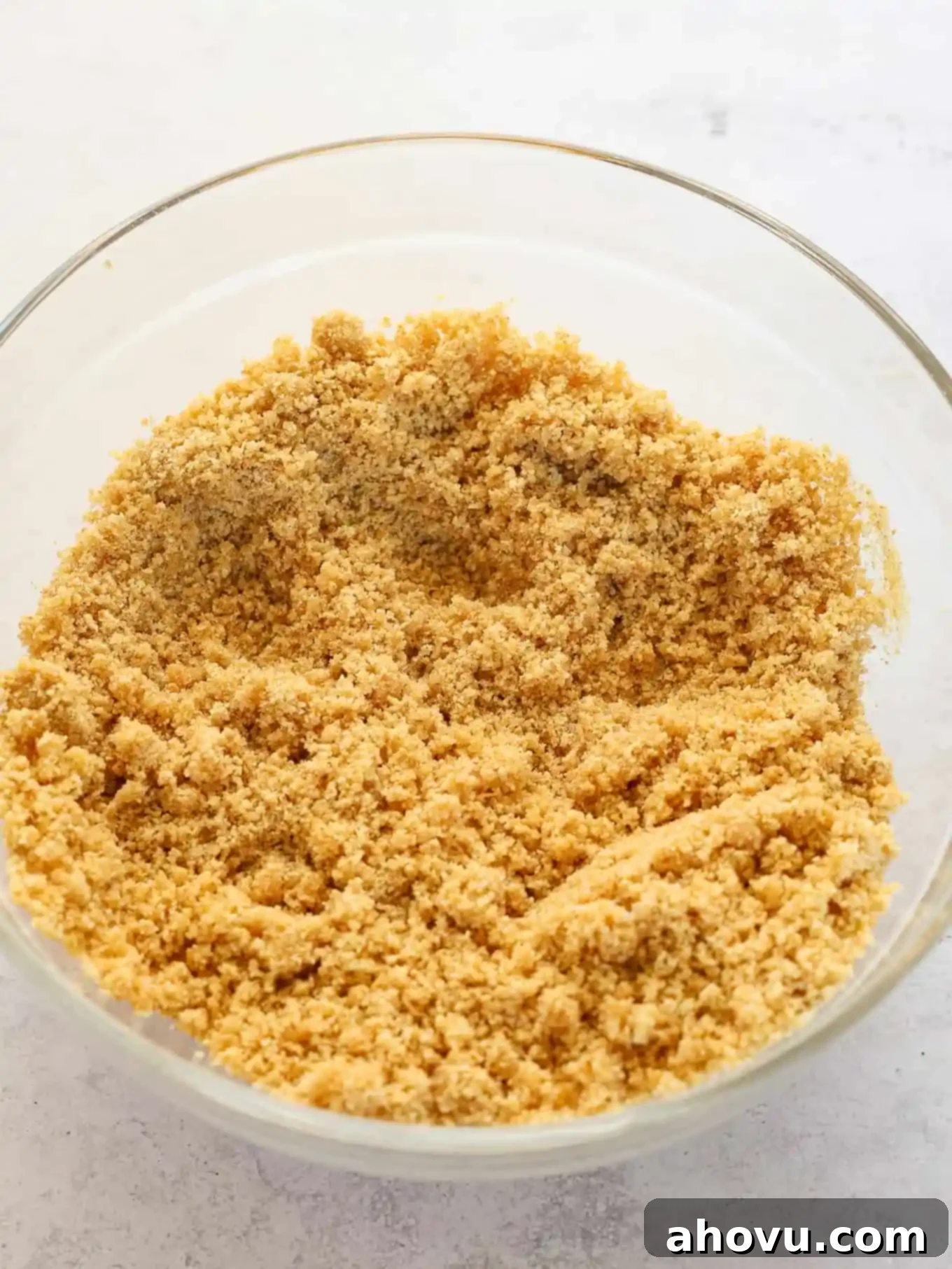 Graham cracker crumb mixture in a glass mixing bowl. 