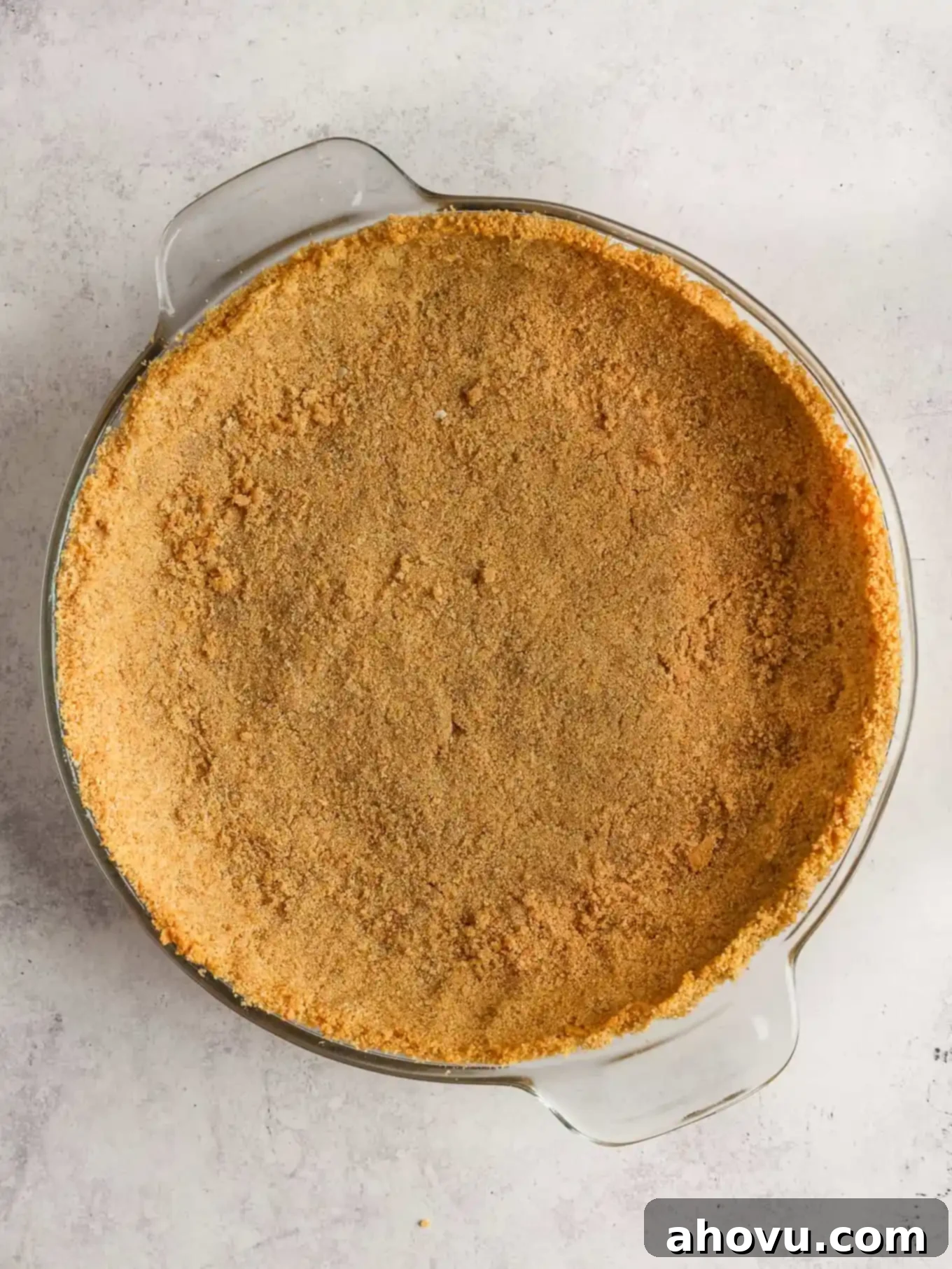 A graham cracker crust in a pie dish, ready to be baked. 