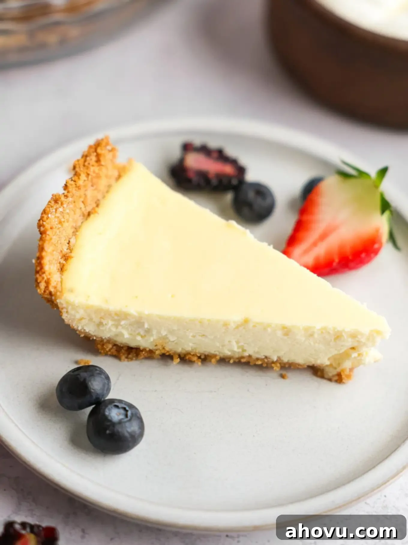 A slice of cheesecake pie on a white plate, with berries. 