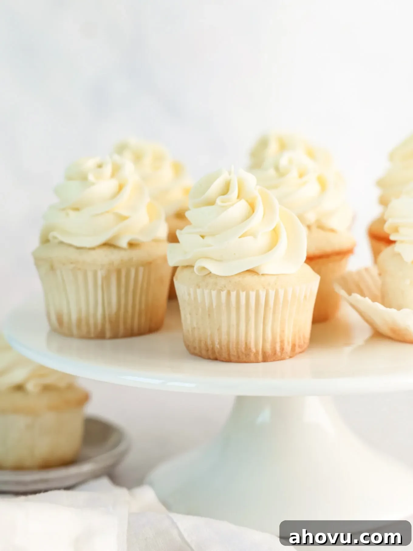 Frosted white cupcakes on a cake stand, elegantly decorated.