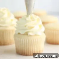 A white cupcake being frosted with vanilla buttercream.