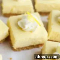 Several lemon cheesecake bars neatly arranged on a piece of parchment paper, highlighting their perfect slices and inviting appearance.