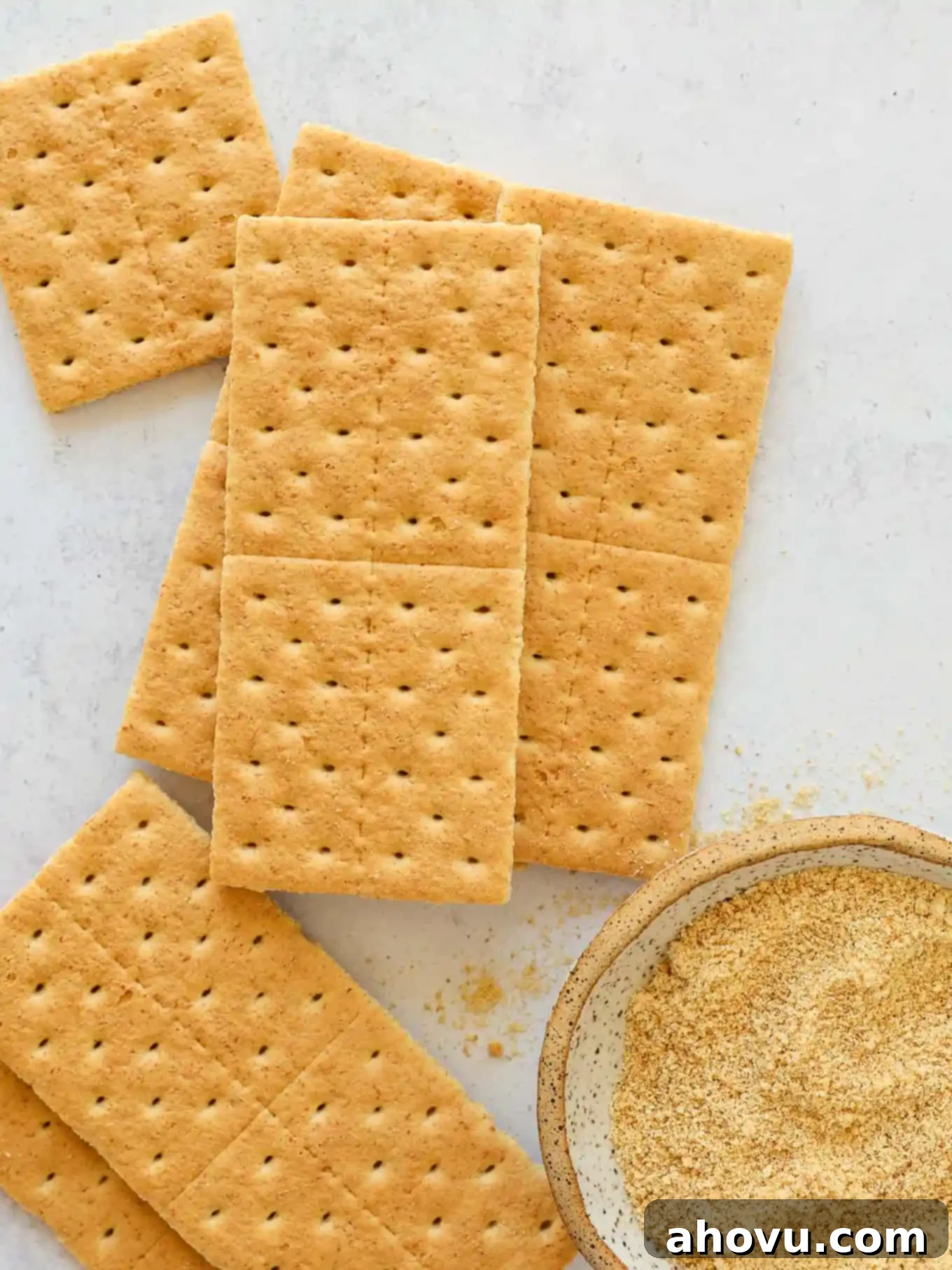 Overhead view of graham cracker sheets next to a bowl of crushed graham cracker crumbs.