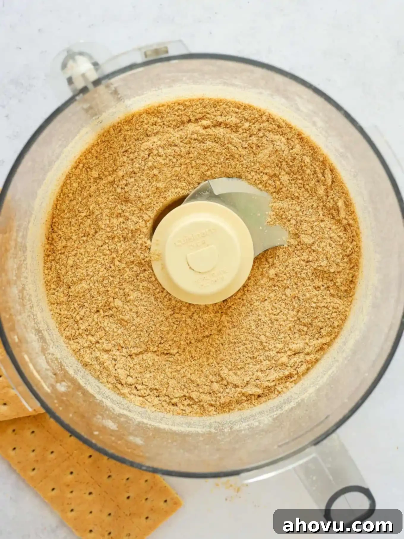 Close-up of graham cracker crumbs being processed in a food processor.