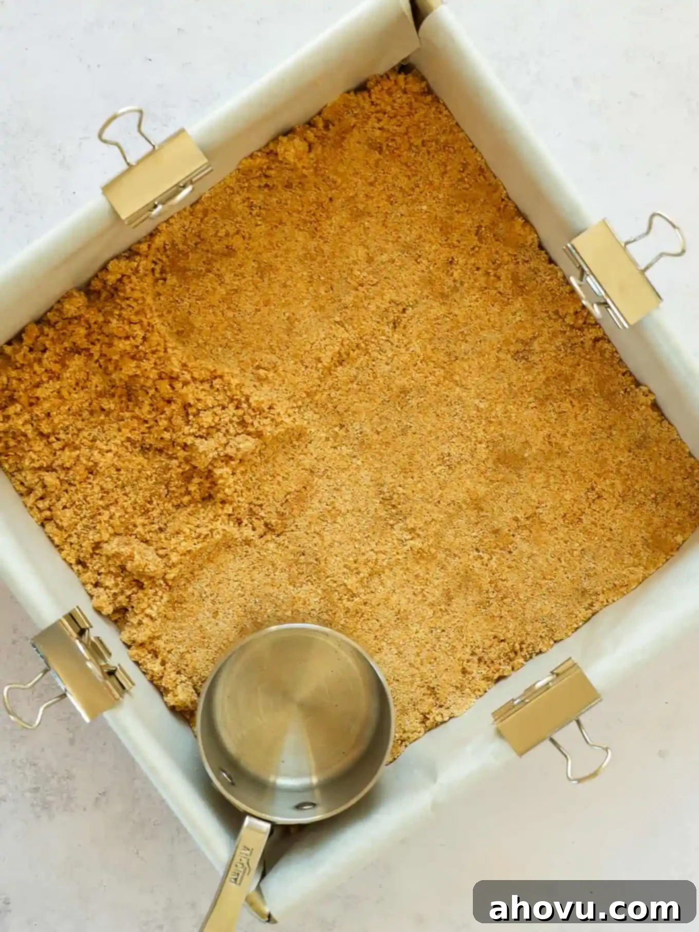 A perfectly pressed graham cracker crust in a square baking dish, ready for filling.