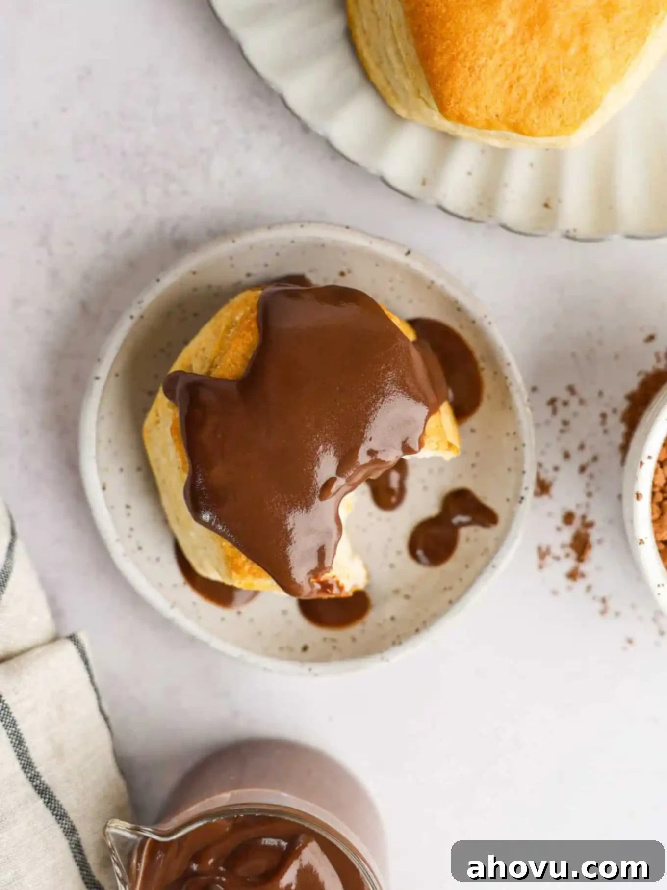 An overhead view of a biscuit topped with chocolate gravy. A bite is missing. 