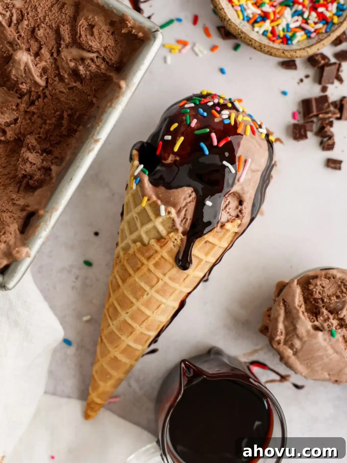 Decadent Chocolate Delight 9 A perfectly scooped chocolate ice cream cone topped with luscious chocolate sauce and colorful sprinkles, lying invitingly on its side.