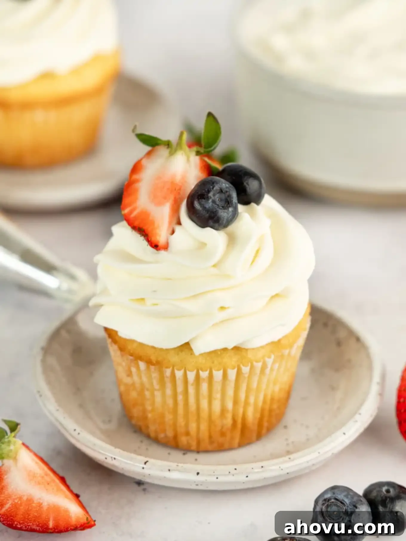 A beautifully frosted cupcake topped with fluffy whipped cream cheese frosting and fresh berries, showcasing its light and airy texture.