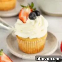 A cupcake topped with whipped cream cheese frosting and fresh berries.
