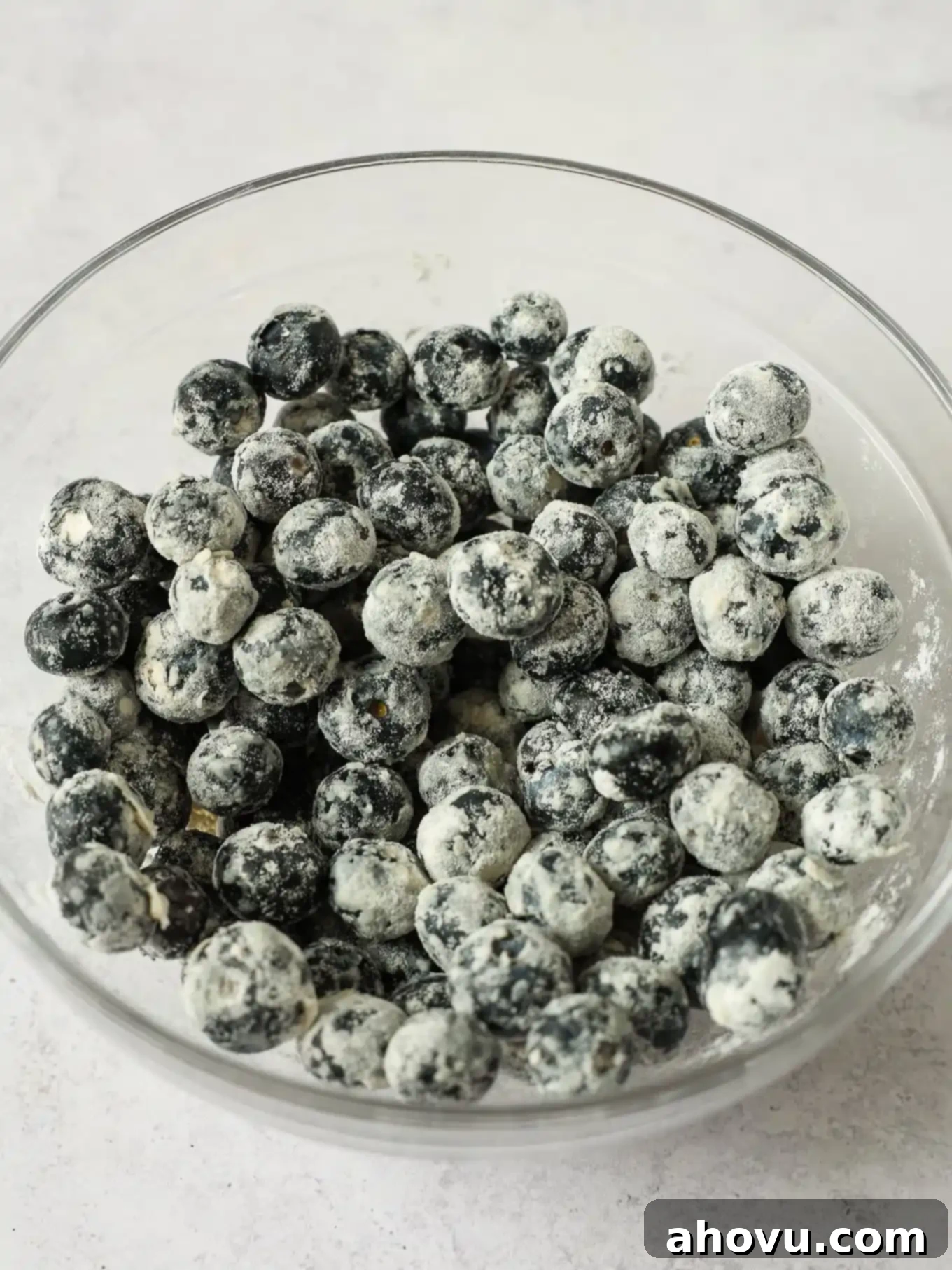A bowl filled with fresh blueberries lightly coated in flour, ready to be folded into cake batter.