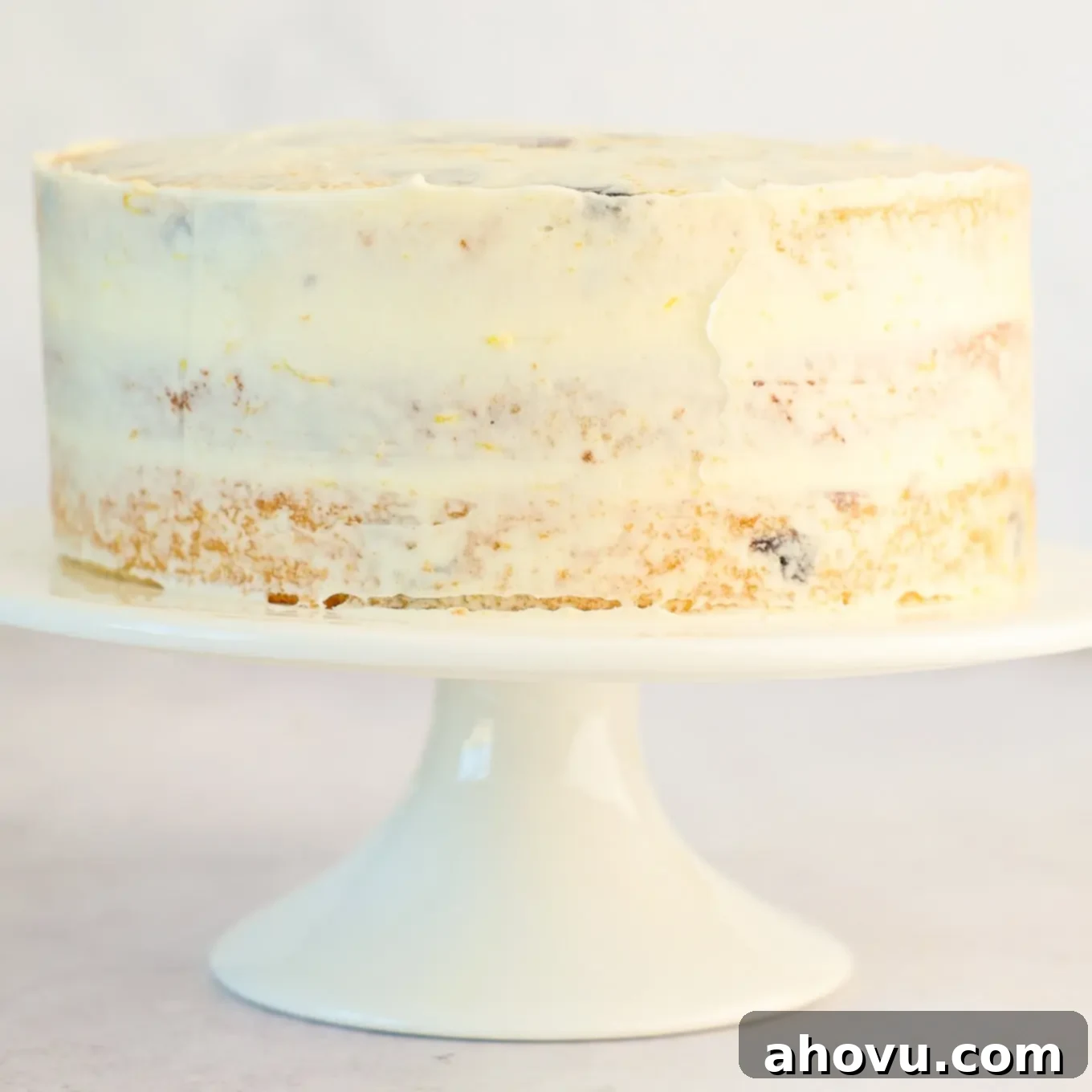A freshly assembled layer cake covered in a thin, even crumb coat of frosting, ready for the final layer of decoration.