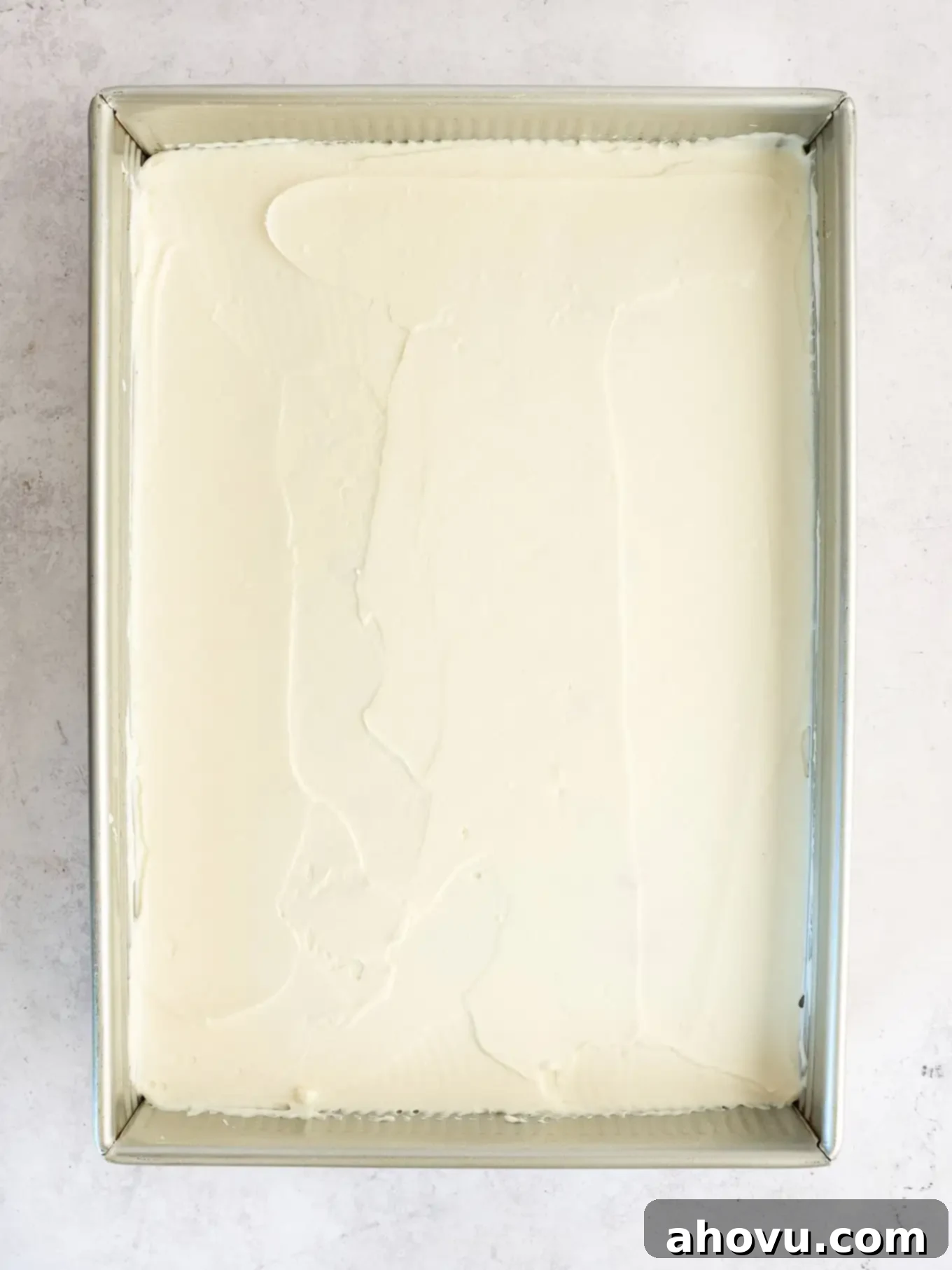 A plain white cake in a 9x13-inch pan, covered with an even layer of frosting.