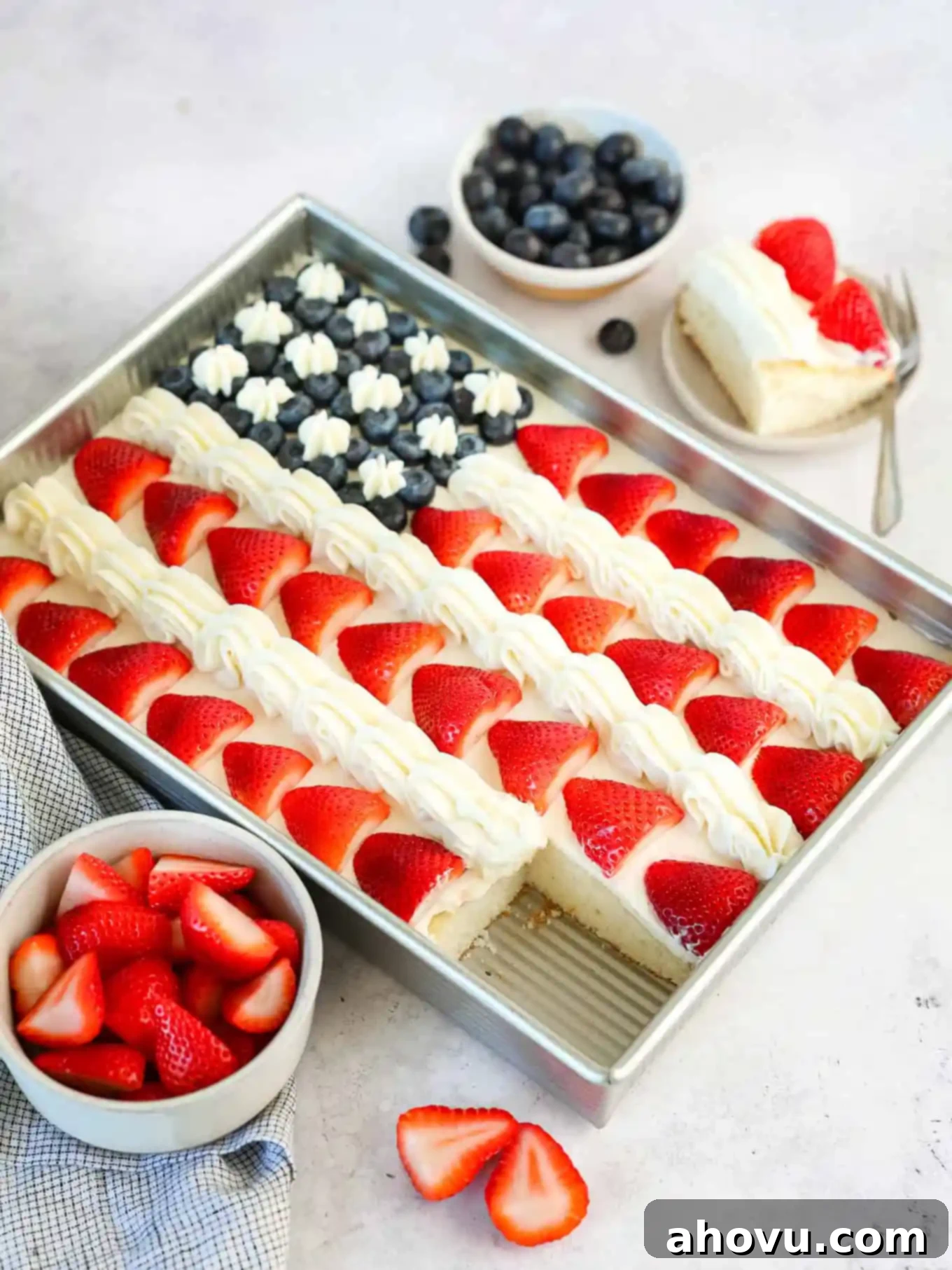 A finished strawberry and blueberry flag cake with a single slice neatly cut out, showcasing its layers.