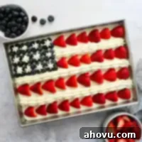 An overhead view of a festive American flag cake decorated with fresh berries and frosting.