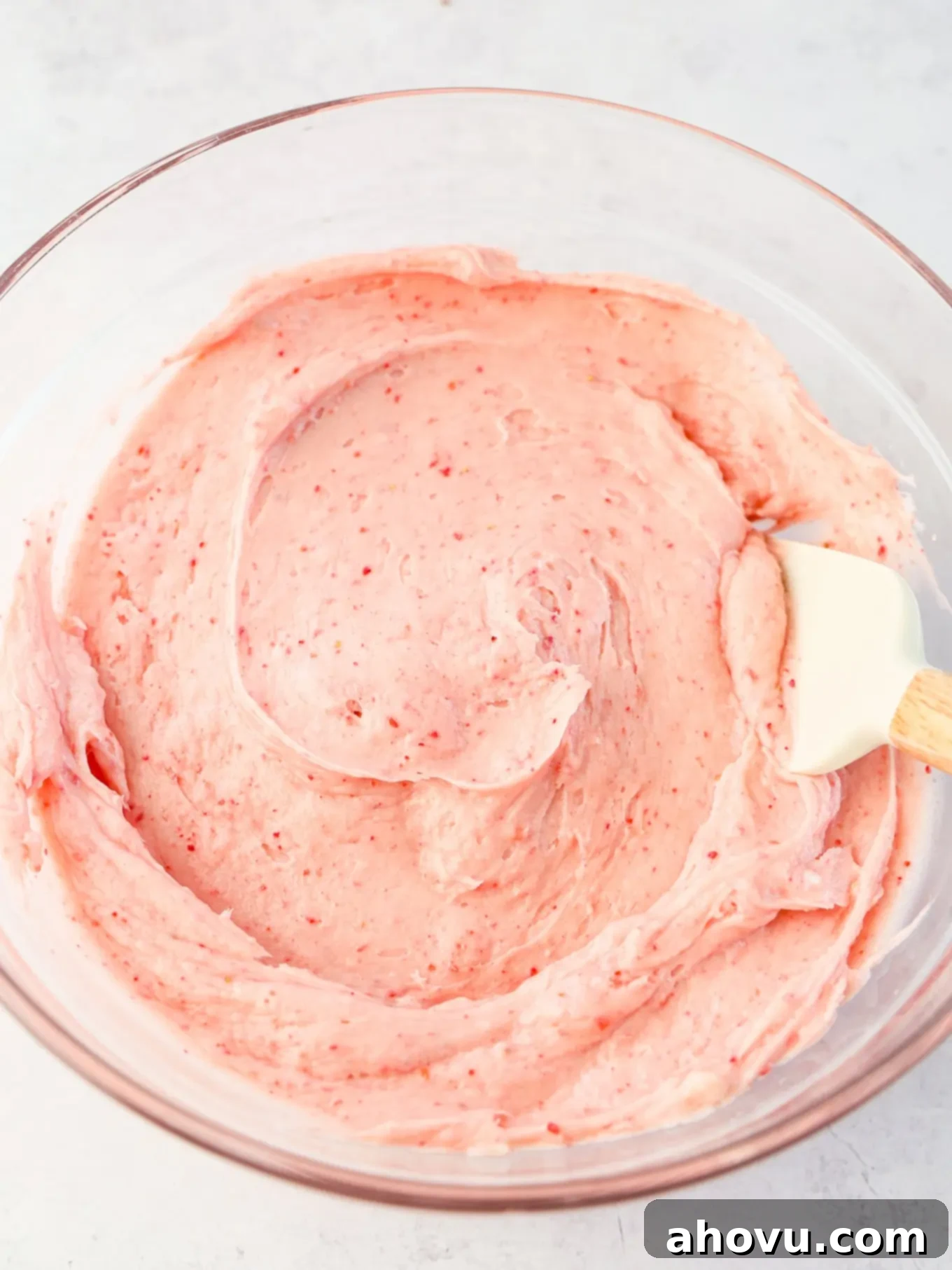 Dreamy Strawberry Cream Cheese Topping 7 Overhead view of creamy strawberry cream cheese frosting in a mixing bowl, with a spatula demonstrating its perfect consistency.