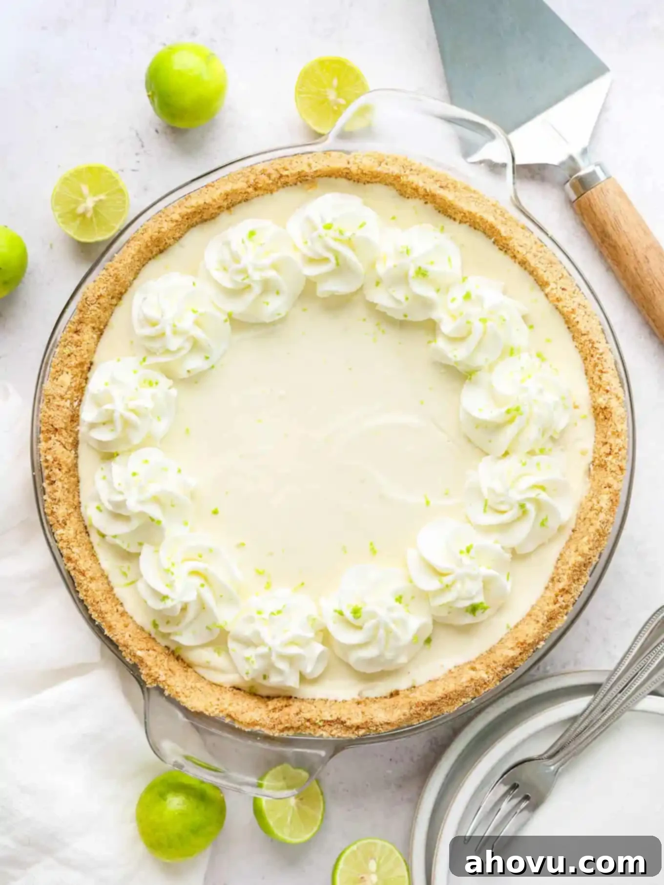 A beautifully garnished no-bake key lime pie, topped with fresh key lime zest and fluffy whipped cream, ready to be served.